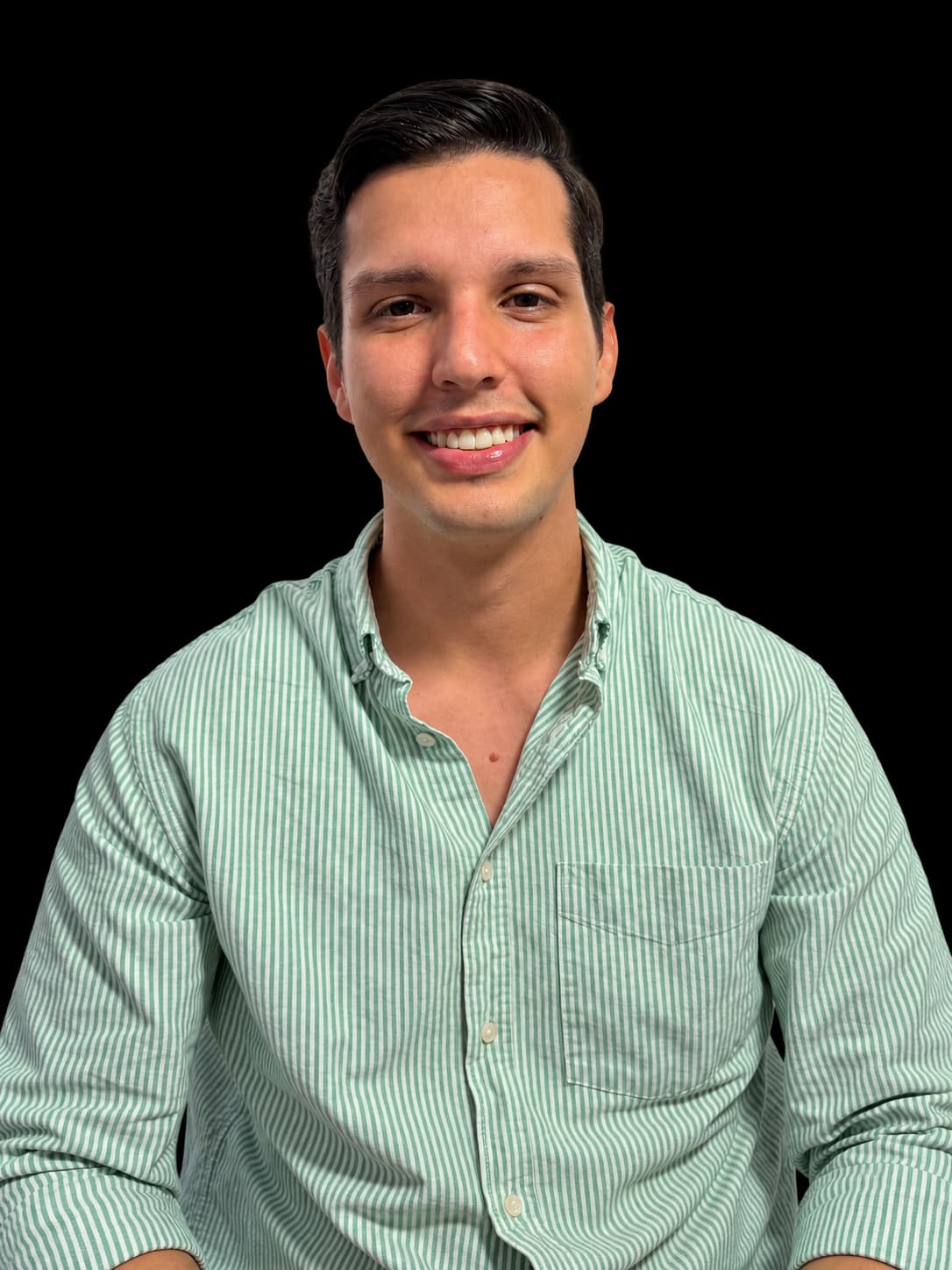 Juan Sebastián Herrera, psicólogo, sonriendo con una camisa verde de rayas